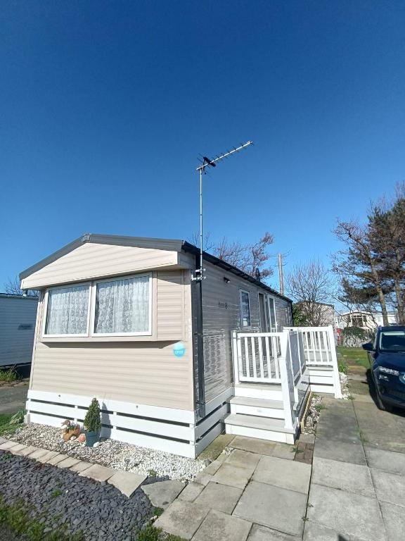 a small white house with a porch and a car at Ollys House in Prestatyn