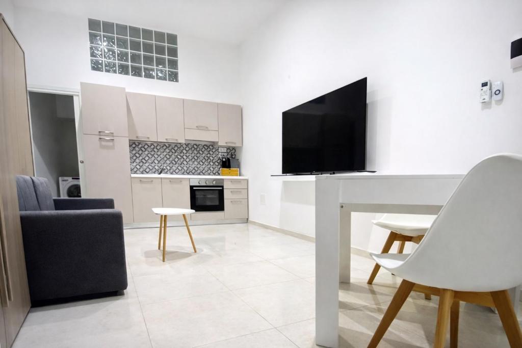 a white living room with a table and a tv at Casa Don Saro in Giardini Naxos