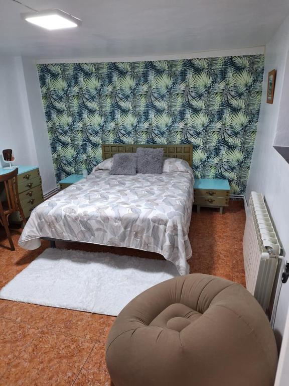 a bedroom with a bed and a ottoman at Casa Rural SERAGAL in El Bonillo