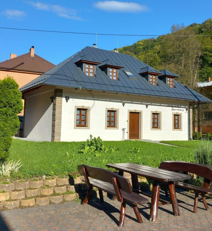 a house with a table and two benches in front of it at Lotrinský Apartmány in Hodruša
