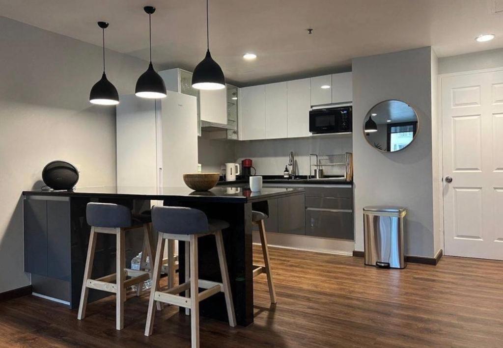 a kitchen with a black counter and stools at Suvannee guesthouse in Ban Khlong Hua Sakae