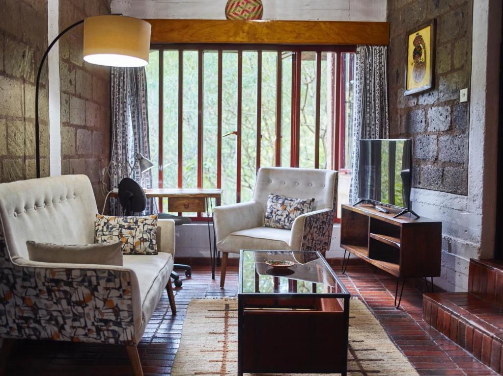 a living room with a couch and chairs and a tv at Villa Rock Stop Falls Gigiri in Nairobi