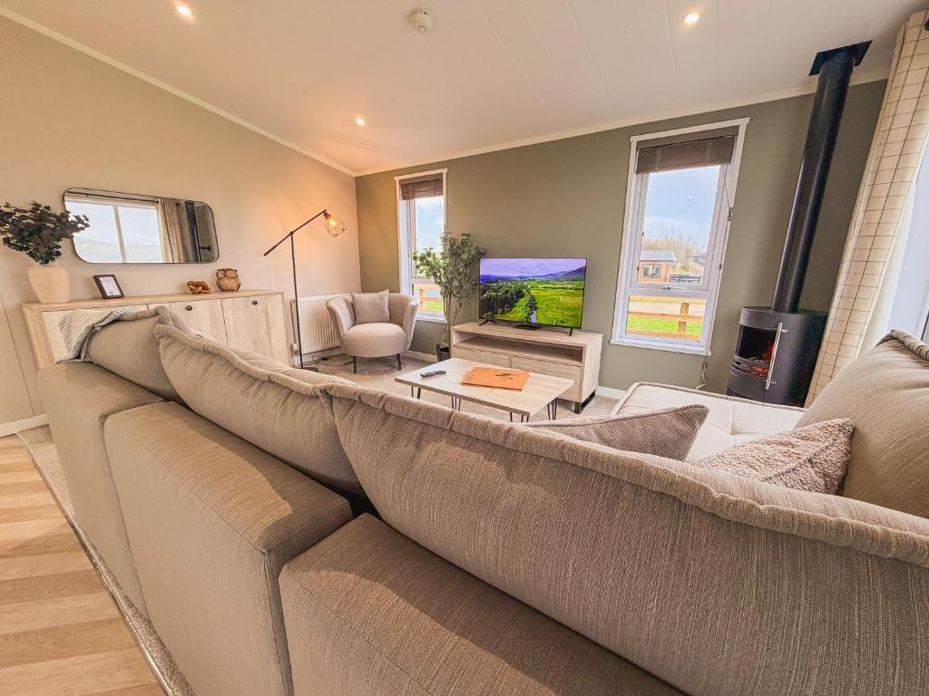 a living room with a large couch and a tv at Sycamore Lodge in Bassenthwaite
