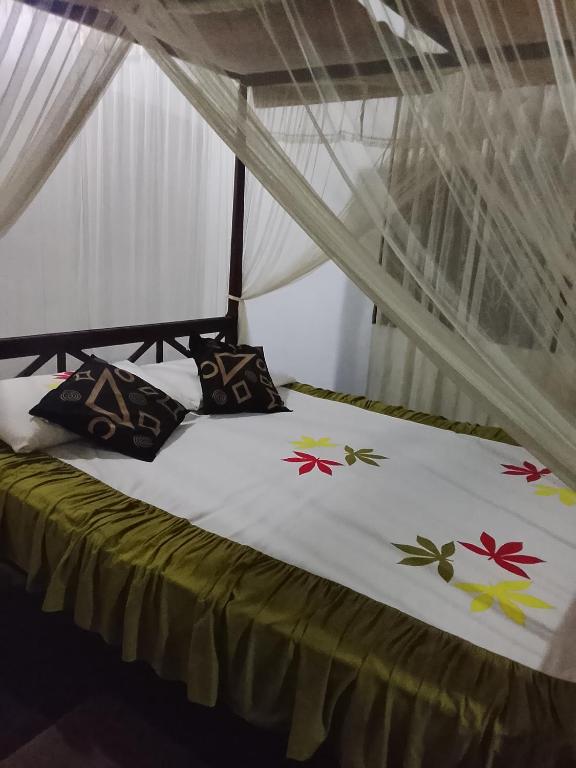 a bed with a white blanket with flowers on it at Peacock rest in Batapola