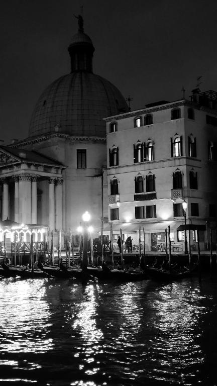 a building with gondolas in the water at night at Hotel Antiche Figure in Venice