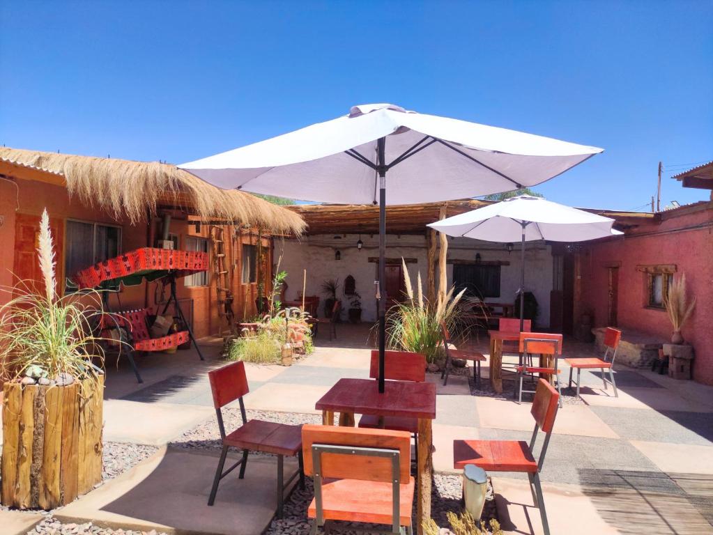 a patio with tables and chairs and an umbrella at Pirca Hostal in San Pedro de Atacama