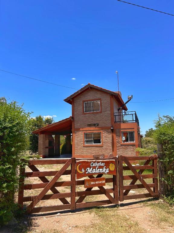 a house behind a wooden fence with a gate at Malenka in Pantanillo