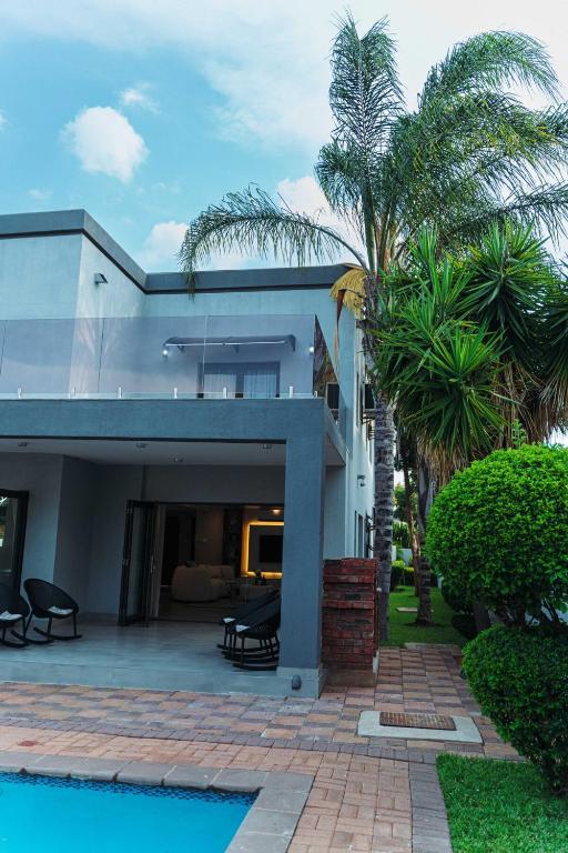 a house with a swimming pool and palm trees at Tlou Luxe stay in Gaborone