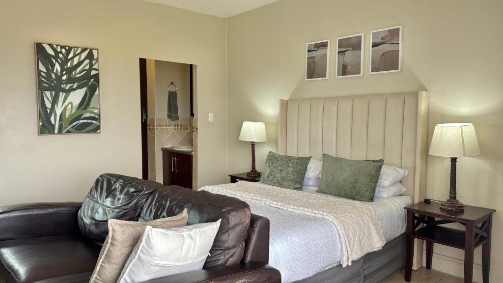 a bedroom with a bed and a leather couch at The olive stay at Ocean view Villas F7 in Port Edward