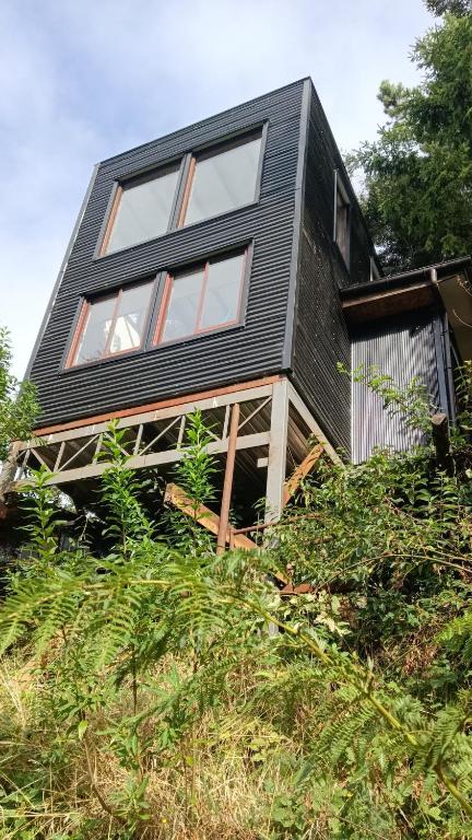 a black house sitting on top of a hill at El Estuario Niebla Cabin in Niebla