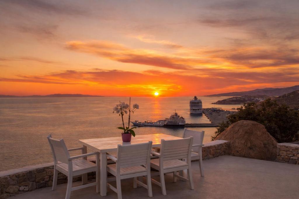 a table and chairs on a balcony with a sunset at Villa Oceania in Tourlos