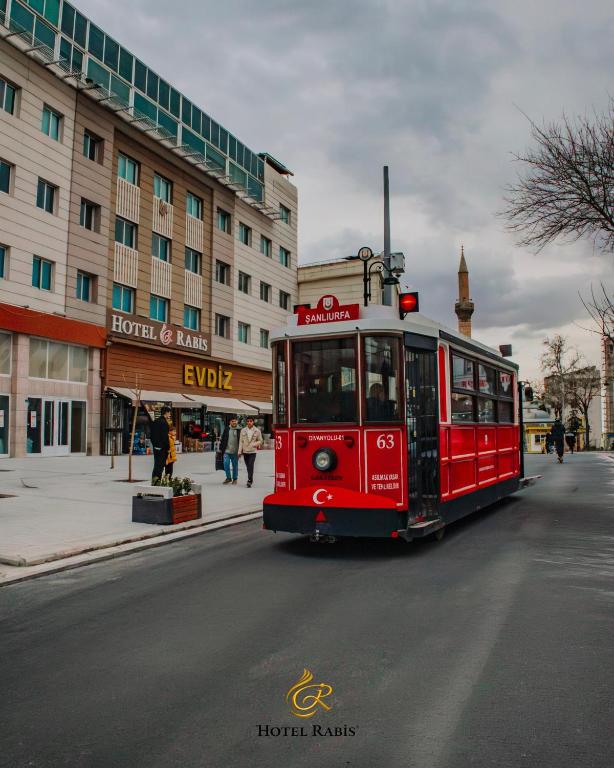 a red trolley car driving down a city street at Hotel RABİS in Urfa