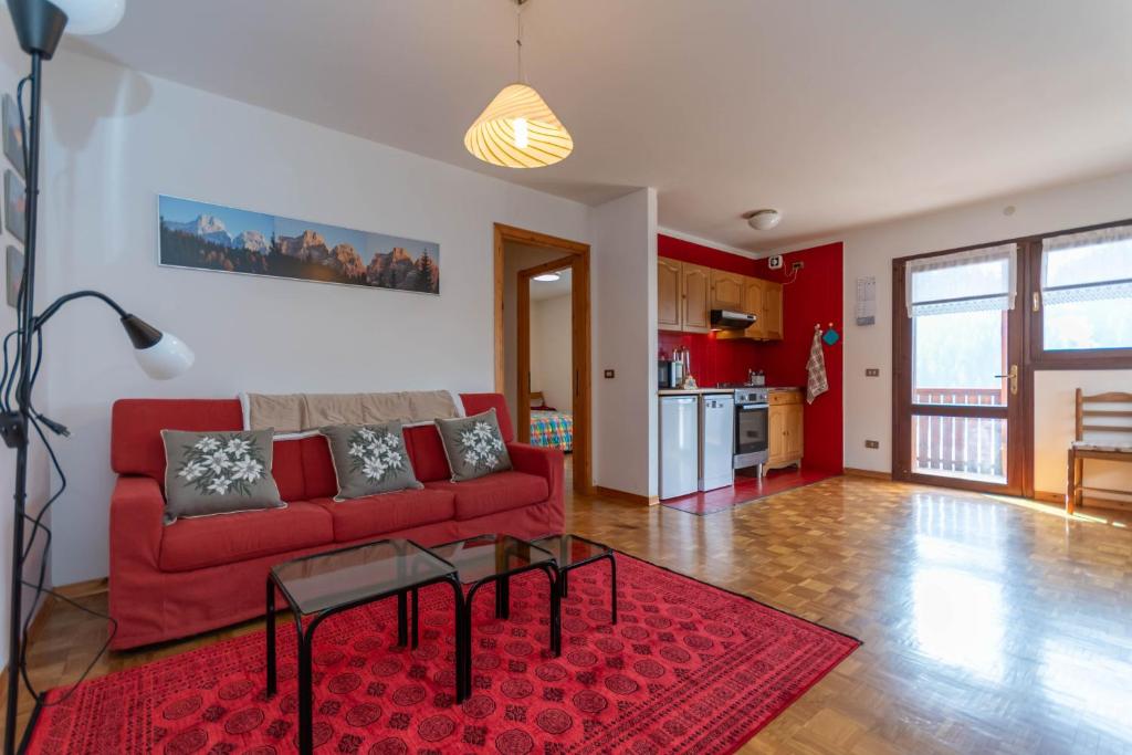 a living room with a red couch and a red rug at Condominio Meraviglia in Selva di Cadore