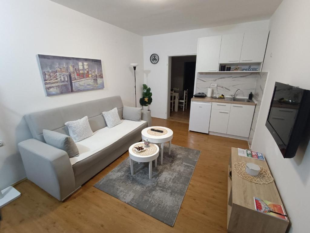 a living room with a couch and a kitchen at Apartman LISA in Niš