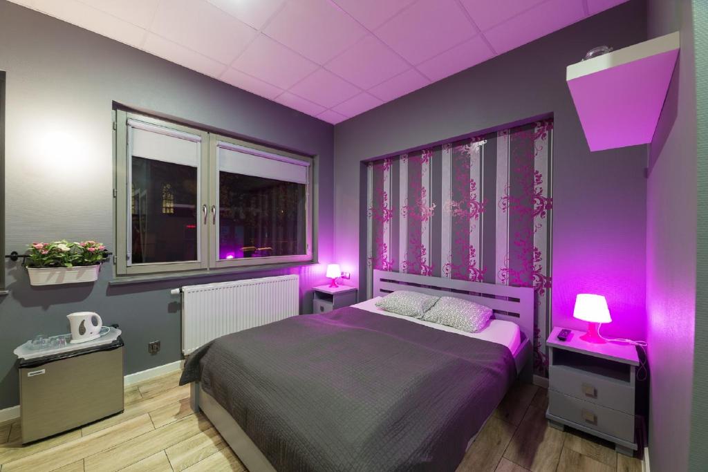 a bedroom with purple walls and a bed with two lamps at Hostel Filip 2 in Gdańsk