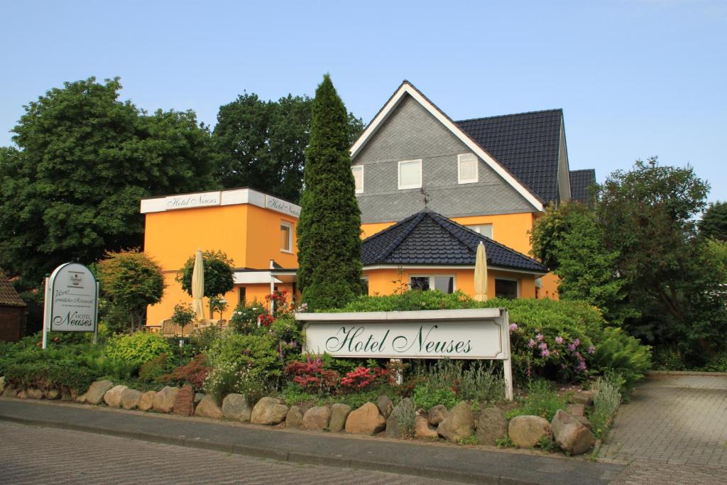 a house with a sign in front of a garden at Hotel Neuses in Cuxhaven