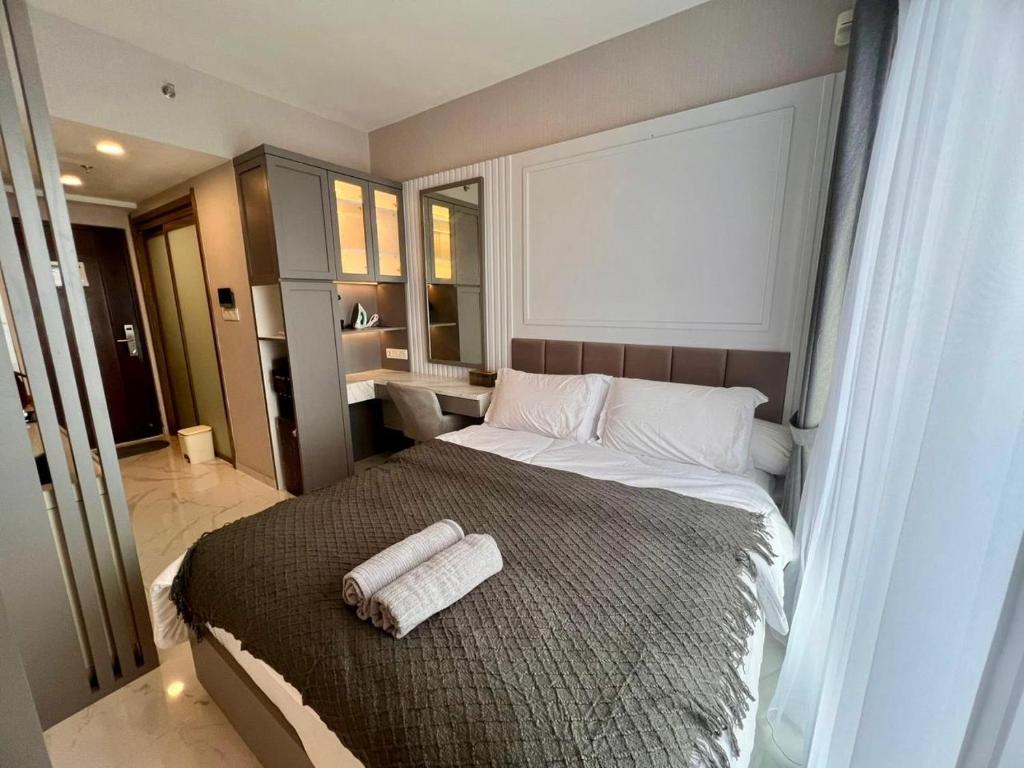 a bedroom with a large bed with two towels on it at Four Living Sky House BSD in Samporo