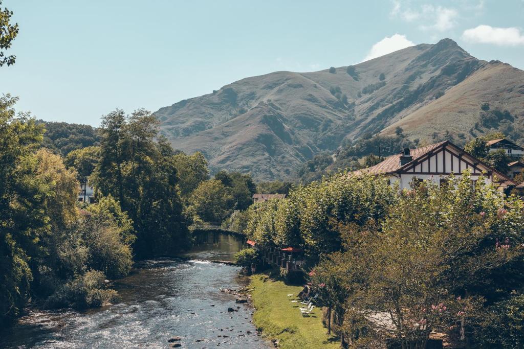 a river in a village with a mountain in the background at Hôtel Arcé - Piscine , Padel, Cheminée in Saint-Étienne-de-Baïgorry