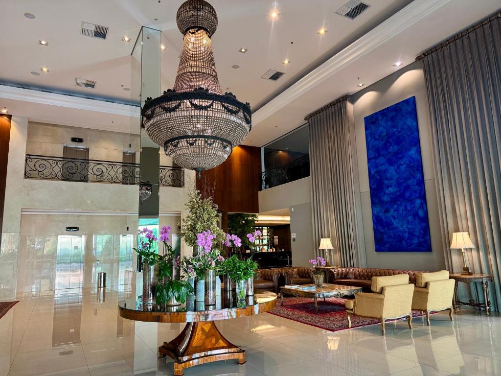 a hotel lobby with a large chandelier and flowers on a table at Flat Mont Blanc Premium in Ribeirão Preto