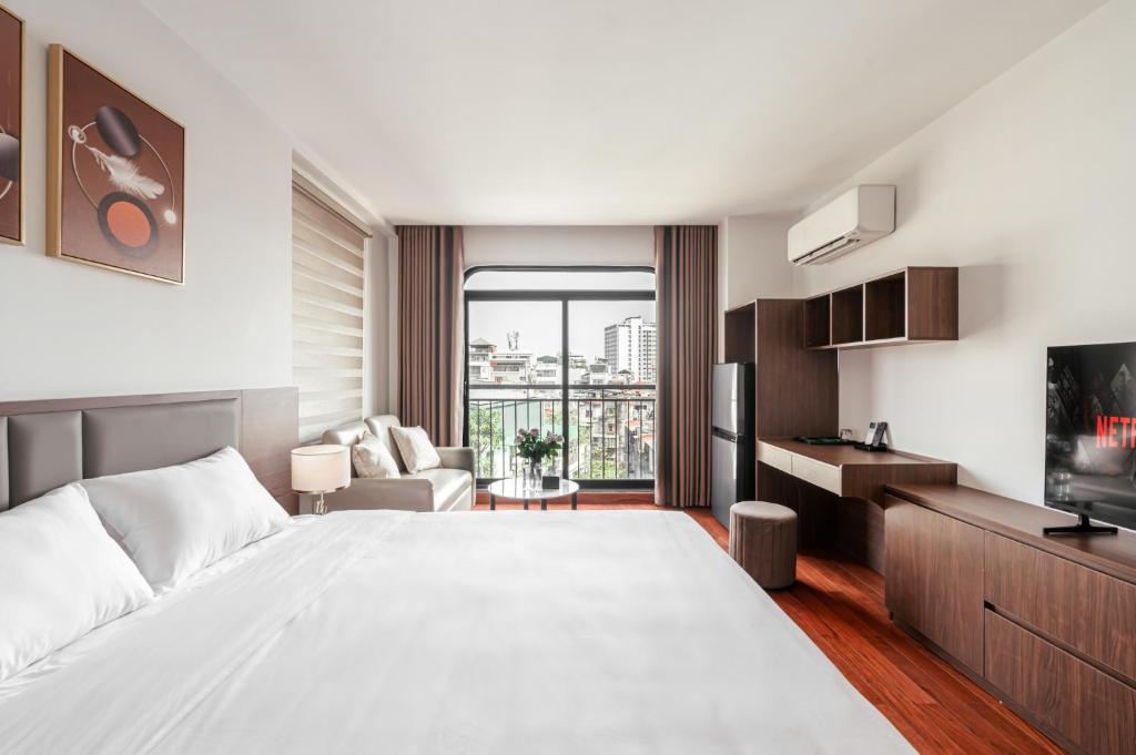 a bedroom with a large white bed and a living room at Luxe Paradise Suites - No34 Alley 260 Đội Cấn in Hanoi
