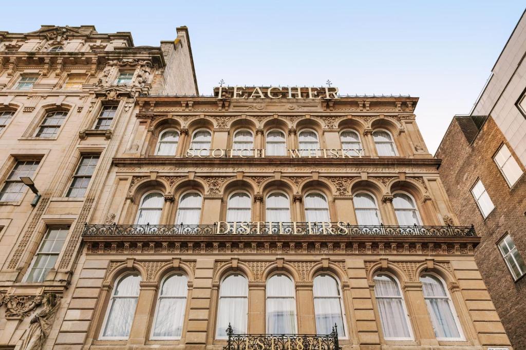 a tall building with a sign on top of it at VCity Suites at The Teacher in Glasgow