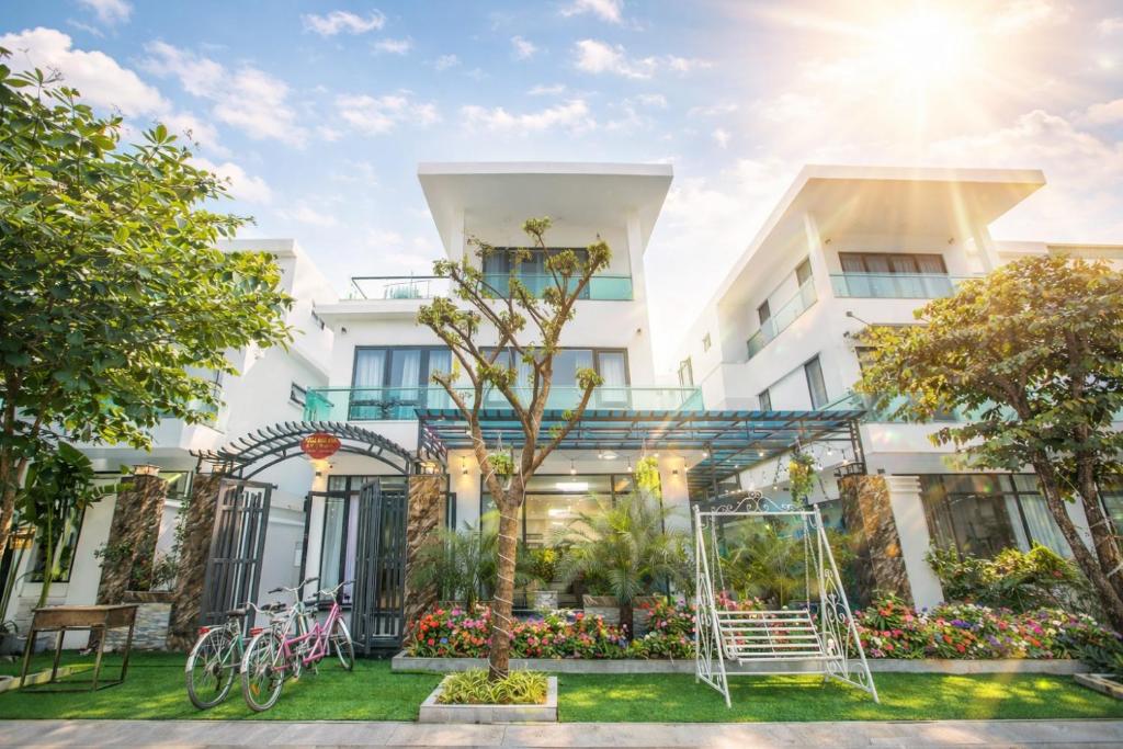 a white building with a tree and a swing at Villa FLC Sầm Sơn Đức Anh in Sầm Sơn
