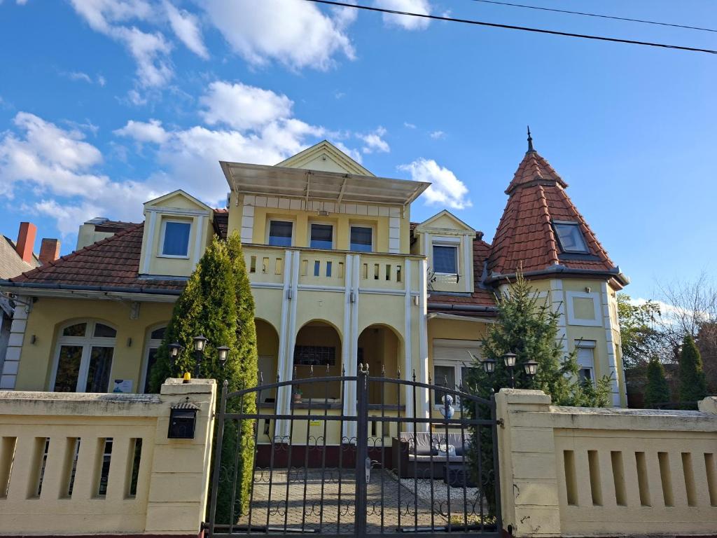 a large yellow house with a gate and a fence at Siófok 7 Apartmanház in Siófok