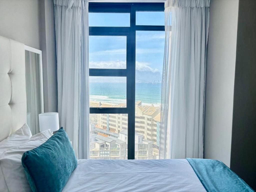 a bedroom with a large window with a view of the ocean at Relaxing Blouberg Beachfront view Apartment in Cape Town