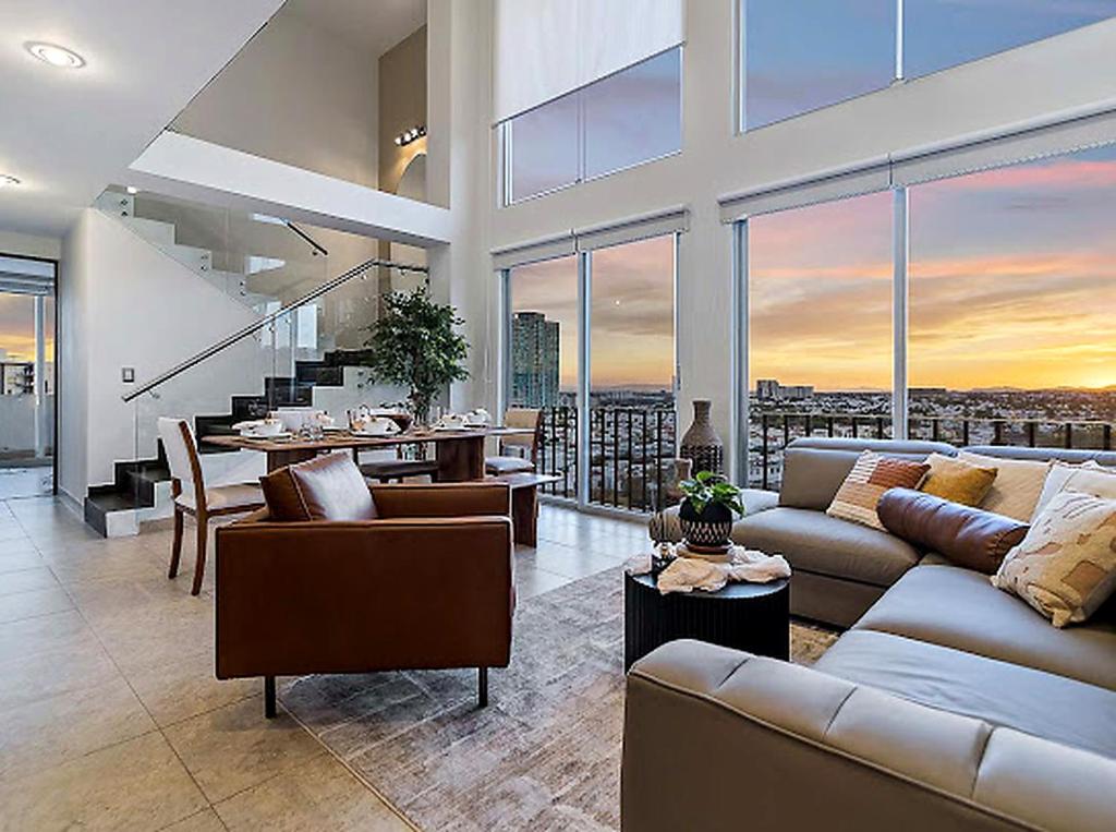 a living room with a couch and a table and some windows at Depa Penthouse en Juriquilla con terraza y alberca climatizada in Juriquilla
