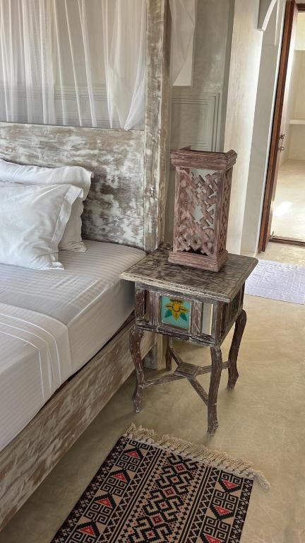 a bed with a night stand next to a table with a nightstand at Kilele-Retreat Suite in Shela