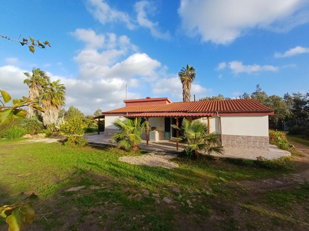 a house with a red roof and palm trees at Podere Al Covo - House, Garden & Vineyard - Alghero in Alghero