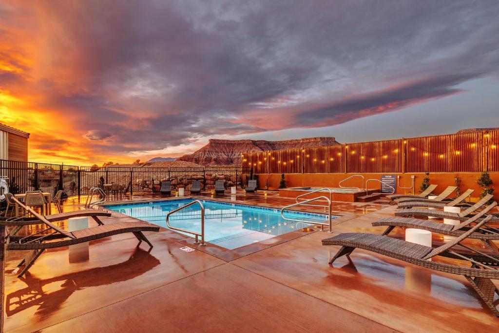 a resort pool with benches and a mountain in the background at The Riv at Zion in Virgin