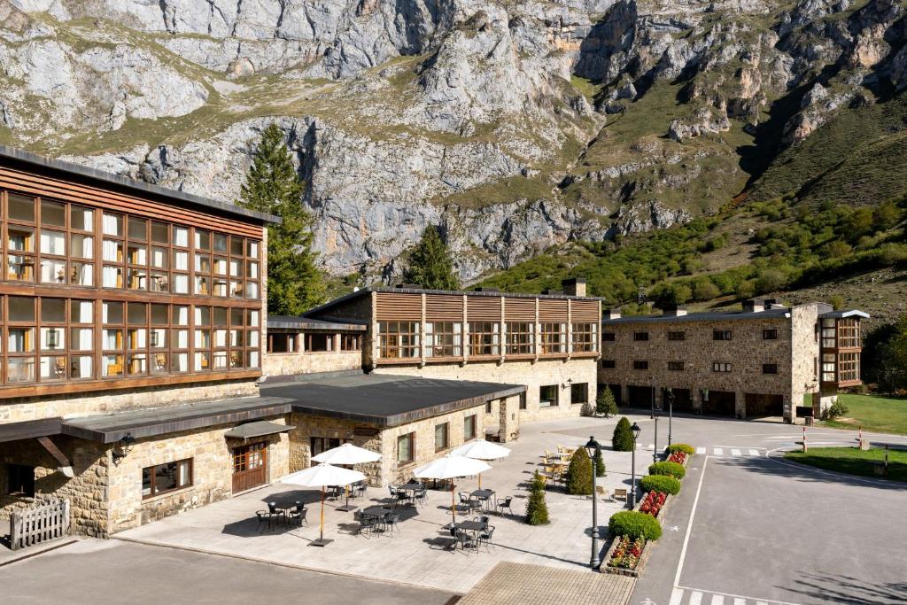 a building with tables and umbrellas in front of a mountain at Parador de Fuente Dé in Fuente Dé