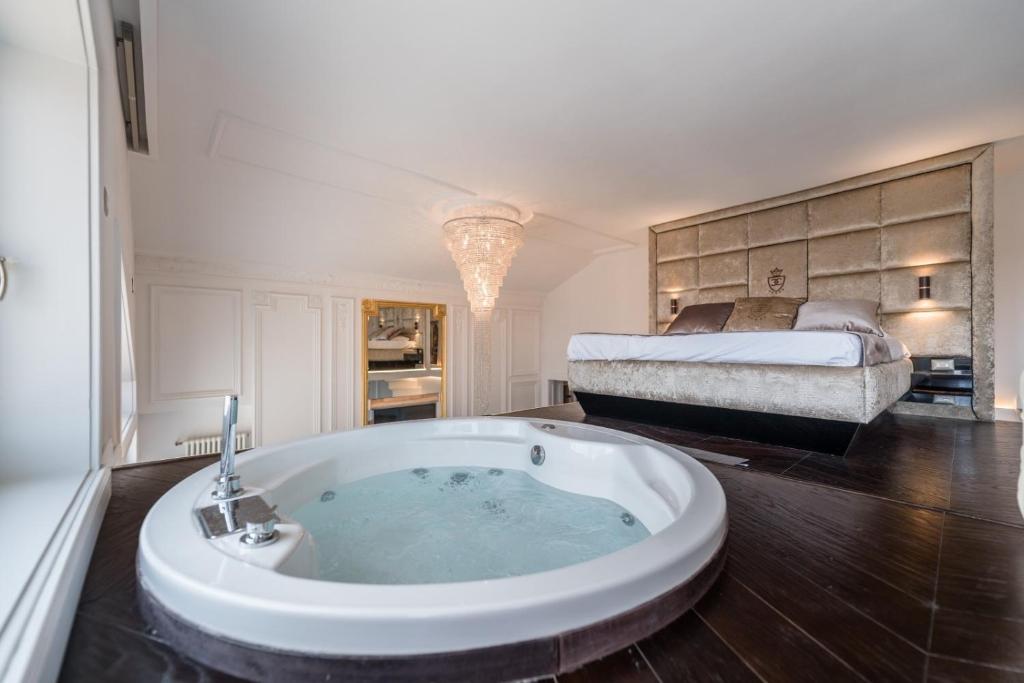 a bathroom with a tub with a bed in the background at Loft City View in Budapest
