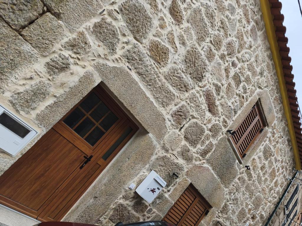 a stone building with a wooden door on it at Casa da Ti Joana in Aranhas