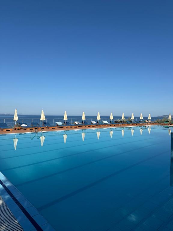 a swimming pool with umbrellas and the ocean in the background at Hotel Bahamas in Sarandë