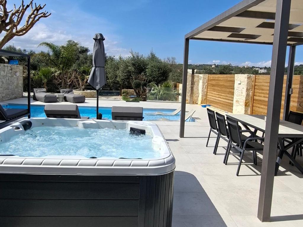 a hot tub in a patio with a table and chairs at Amare suite 2 in Perivólia