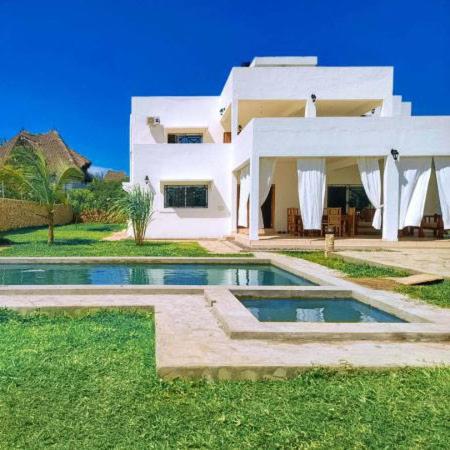 a large white house with a swimming pool in front of it at Villa Franet in Watamu