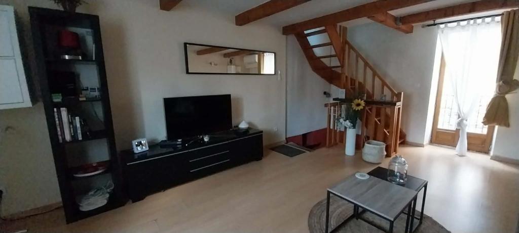a living room with a flat screen tv and a table at A L ESCALE PASSA PAÏS in Le Poujol-sur-Orb