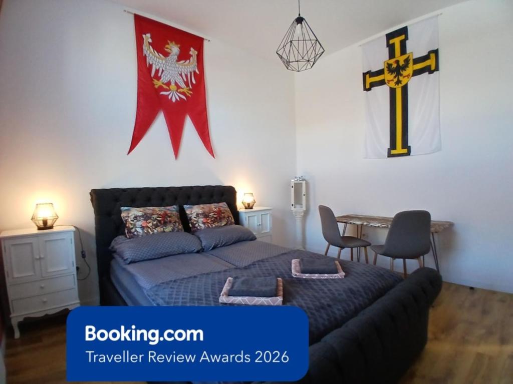 a bedroom with a bed and a cross on the wall at Apartamenty Zakonne "Apartament Komtura" in Malbork