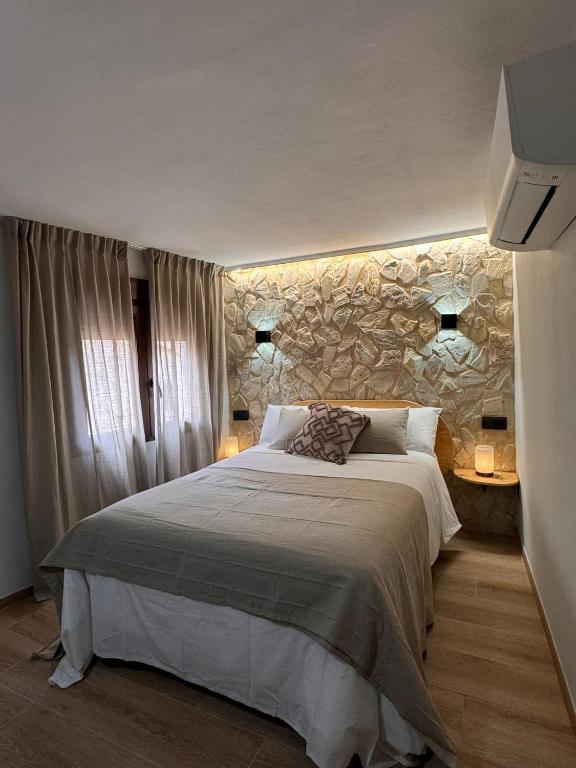 a bedroom with a large bed and a stone wall at La Rambla in Albarracín
