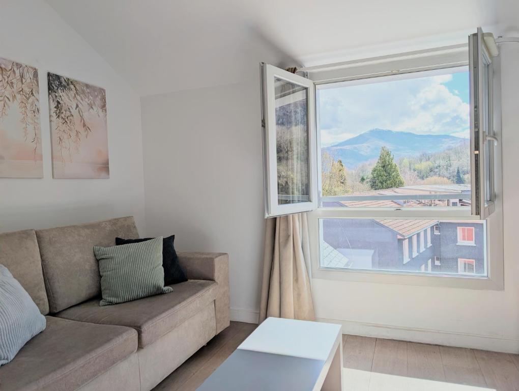 a living room with a couch and a large window at Studio détente proche Sanctuaires in Lourdes