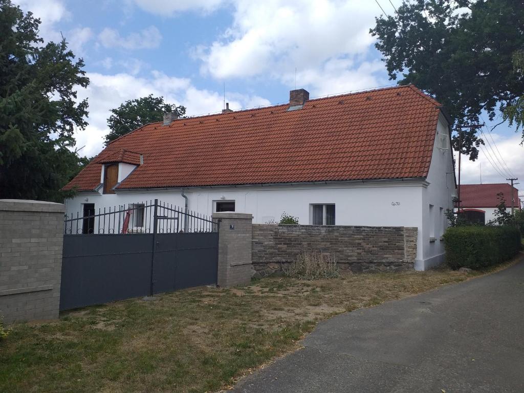 a white house with a red roof and a fence at Chalupa u dubu Horní Ostrovec in Písek