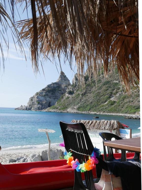 a table and chairs on a beach with the ocean at I Settembrini in Capo Vaticano