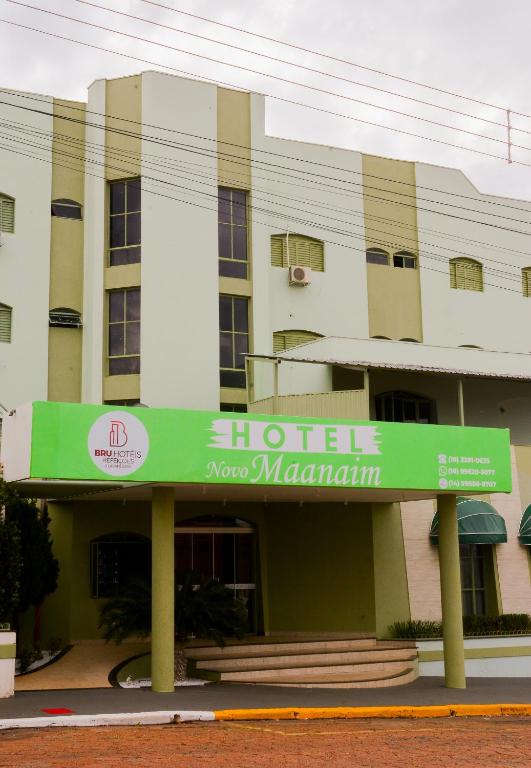 a hotel with a green sign in front of a building at Novo Maanaim Hotel in Presidente Epitácio