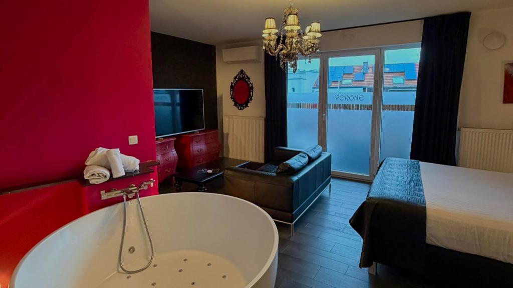 a room with a tub and a bed and a television at L'écrin des Vennes - Liège centre in Liège