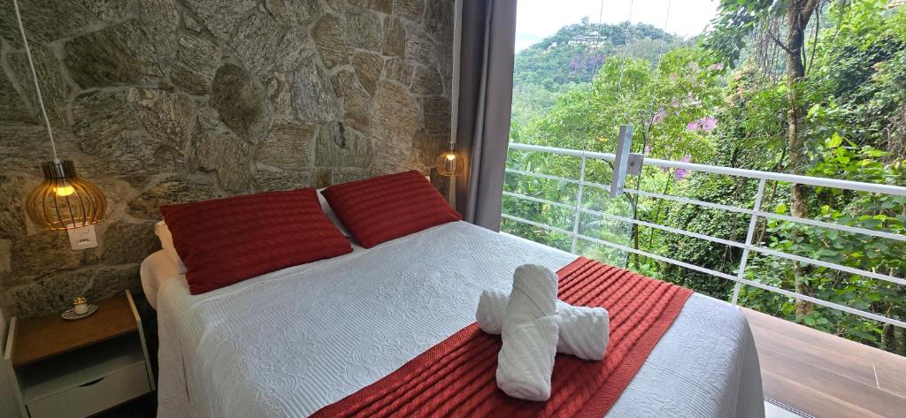 a bedroom with a teddy bear on a bed with a window at Estúdio Beija-flor Itaipava in Araras Petropolis