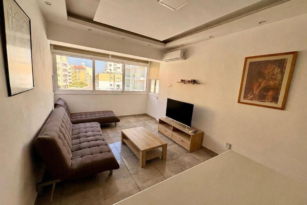 a living room with a couch and a tv at Jane 202 cosy 1 bedroom in Larnaca
