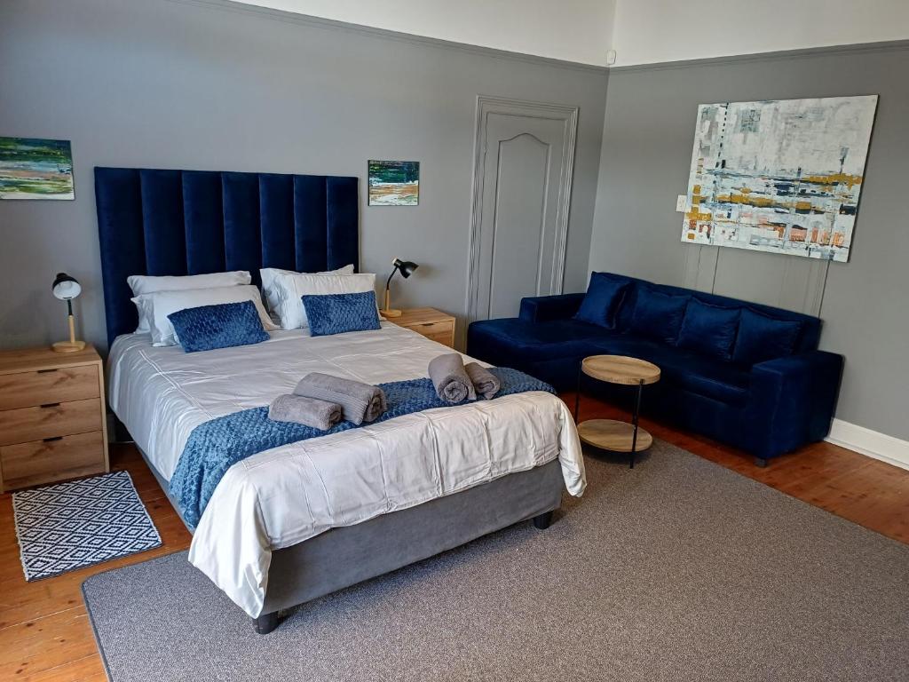 a bedroom with a large bed and a blue couch at Wembley guesthouse in Plumstead