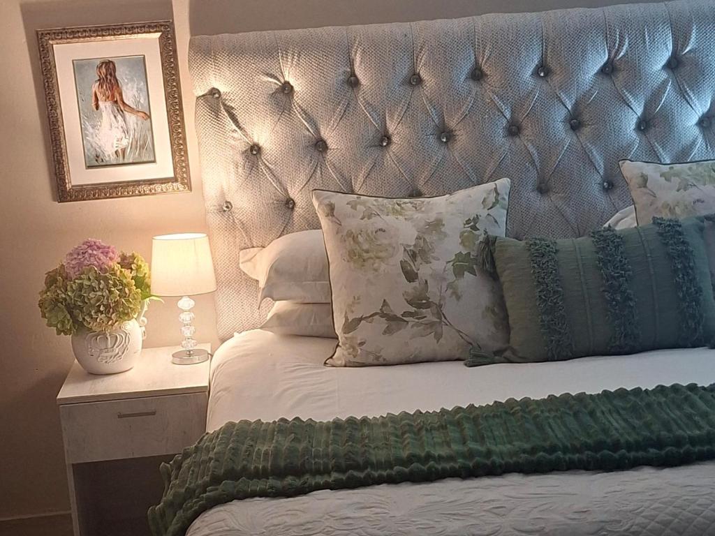 a bed with a blue headboard and a table with a lamp at Kaleb Guesthouse in Bethlehem